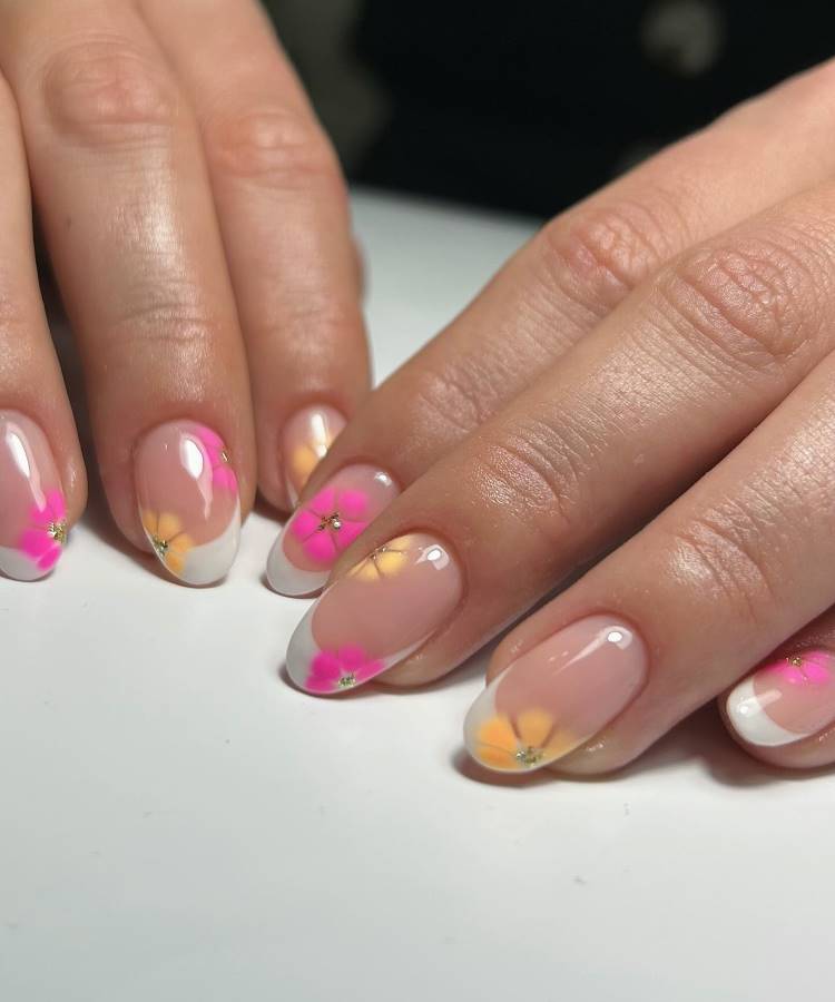 Unhas de gel decoradas com esmalte translúcido nude, pontas brancas e flores coloridas em tons de rosa e amarelo com detalhes centrais prateados. O design fresco e delicado oferece uma estética primaveril e elegante, destacando-se pelo acabamento brilhante.





