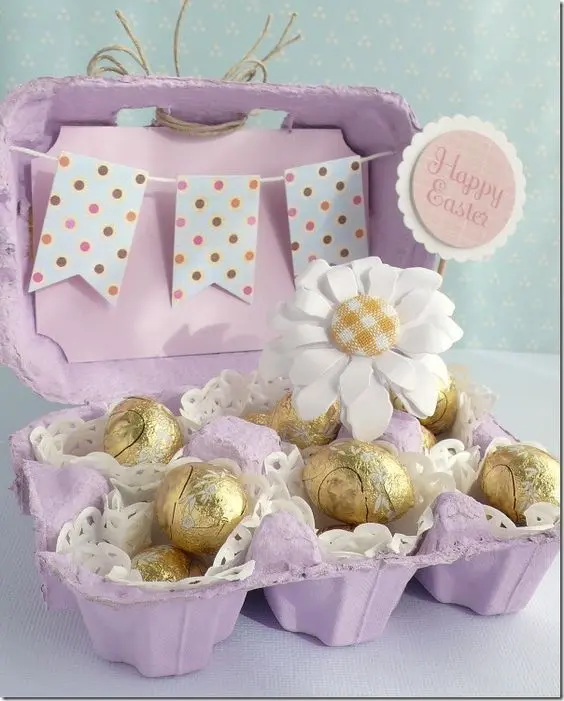 Caixa de ovo pintada de roxo com ovos de Páscoa embrulhados em papel dourado