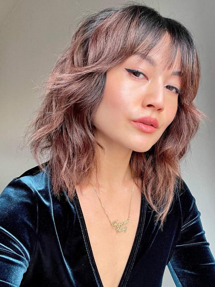 Mulher asiática com cabelo rosa desbotado em corte shaggy curto