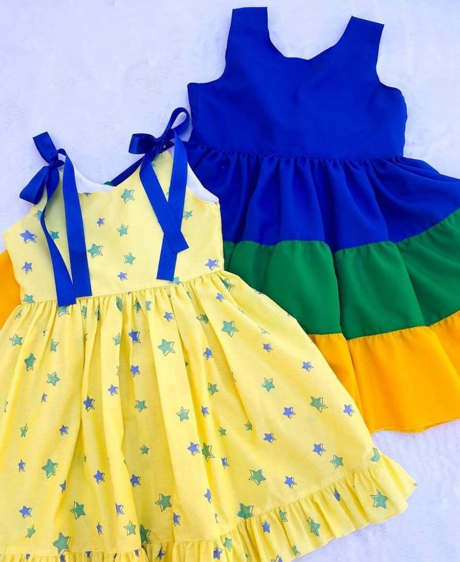 Imagem com fundo branco. No centro, dois vestidos verde, amarelo e azul para a Copa do Mundo. 