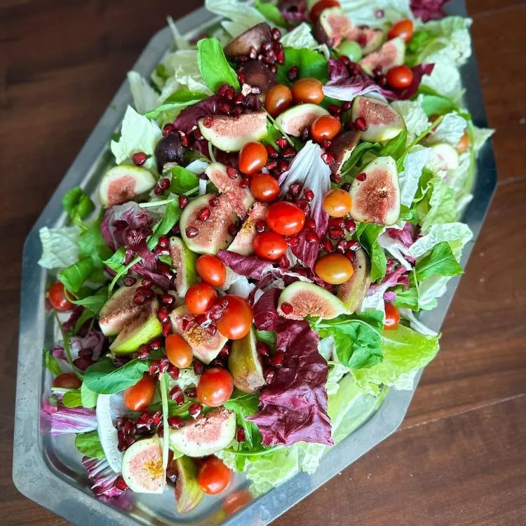 Um prato de salada de folhas com tomate e figos