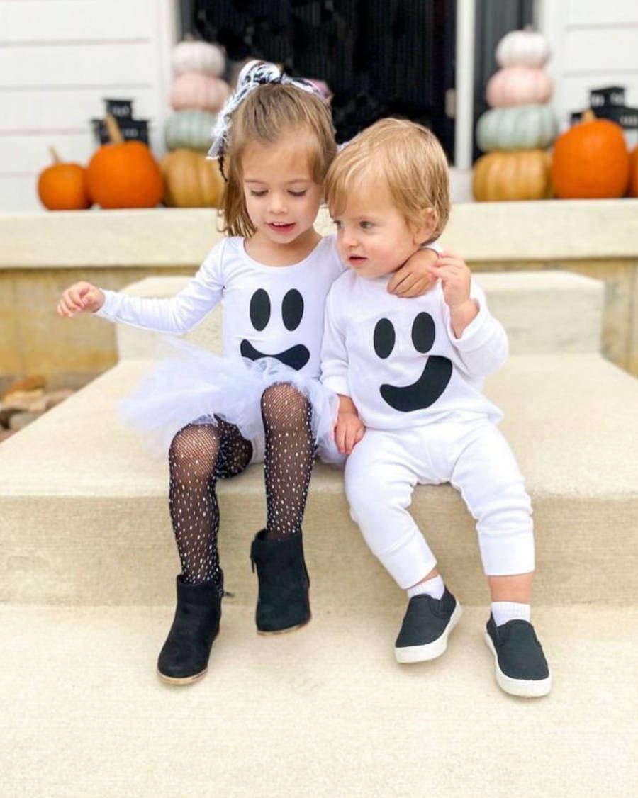 Foto de irmãos abraçados em uma escada com fantasia de fantasma para o Halloween
