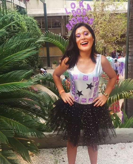 Mulher de pele clara com tiara de louca dos signos com body de signos  e saia de tule preta