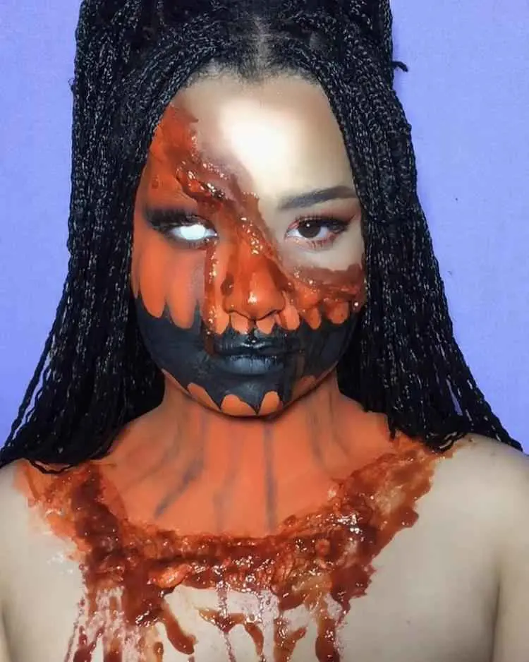 Mulher de pele negra usando maquiagem de abóbora assustadora, com boca preta