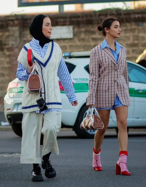A direita blusa listrada com sobreposição blazer xadrez, a esquerda blusa listrada com sobreposição tricô Modelos usam camisa listrada com sobreposição