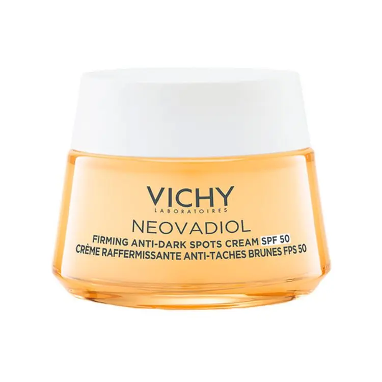 A imagem mostra um pote do creme Vichy Neovadiol Firming Anti-Dark Spots Cream SPF 50. A embalagem é de cor laranja-claro translúcido com uma tampa branca. O produto é um creme reafirmante e anti-manchas marrons, com fator de proteção solar 50.

