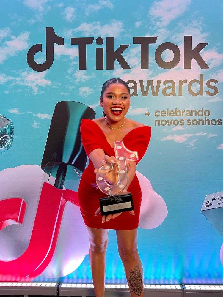 Eloa Almeida de vestido vermelho segurando prêmio do TikTok Awards 2023