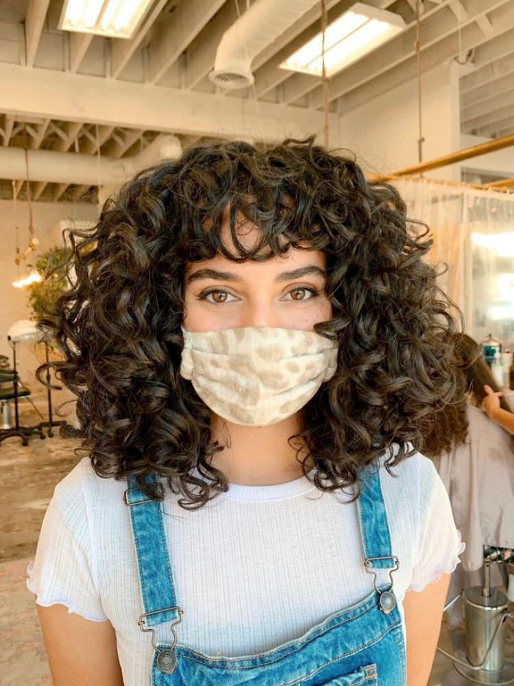 Mulher com cabelo cacheado volumoso, curto e repicado