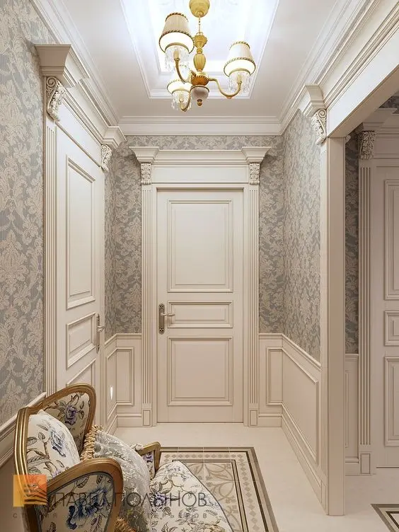 Corredor com papel de parede azul e bege, portas com ornamentos e moldura boiserie, sofá bege com flores azuis 