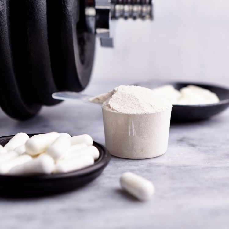 foto de suplementos apoiados em mesa ao lado de peso de academia
