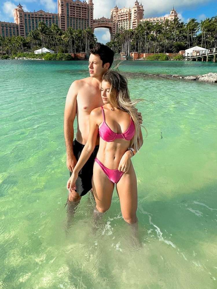 Enaldinho de bermuda preta e Anninha de biquini rosa em praia