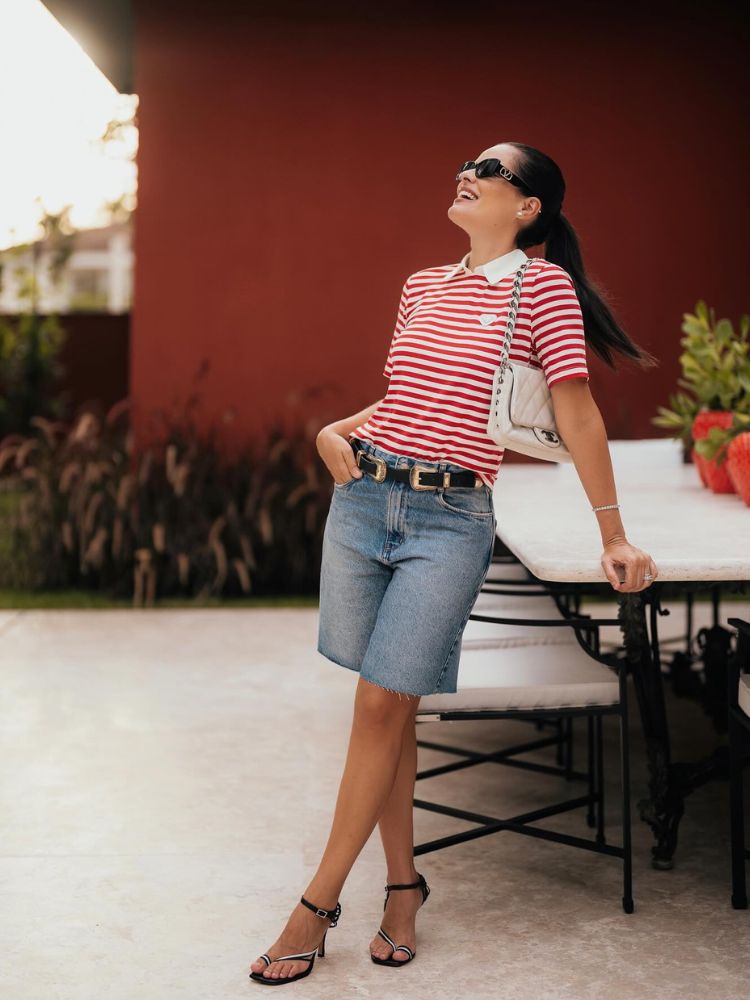 Mulher de pele clara de bermuda jeans e camisa polo branca e vermelha