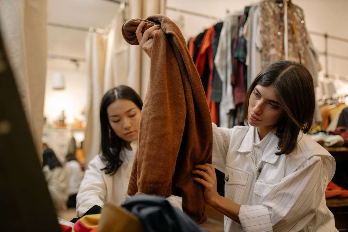 2 mulheres escolhendo roupas em brechó
