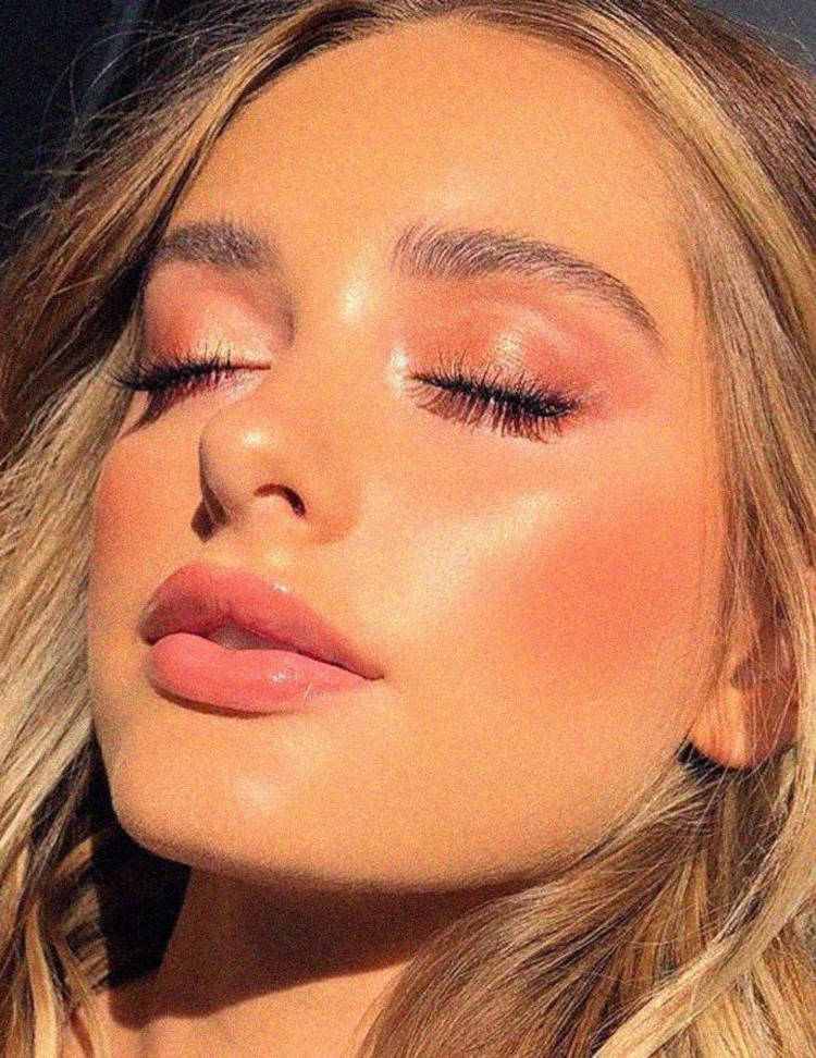 Mulher de pele clara com maquiagem sutil e pele glow 