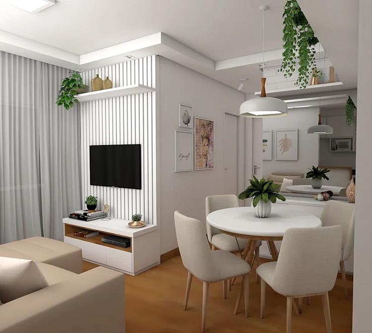 foto de sala integrada com sala de jantar, apartamento em cores claras, branco e cinza. O sofá é bege, disposto em frente à televisão em painel ripado branco. Ao lado, mesa branca redonda de quatro lugar e espelho ao fundo.