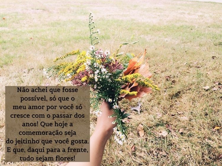 Pessoa de pele clara segurando buquê de flores em gramado e frase "Não achei que fosse possível, só que o meu amor por você só cresce com o passar dos anos! Que hoje a comemoração seja do jeitinho que você gosta. E que, daqui para a frente, tudo sejam flores!"