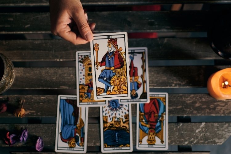 Taróloga com cartas na mesa e segurando o Rei de Espadas