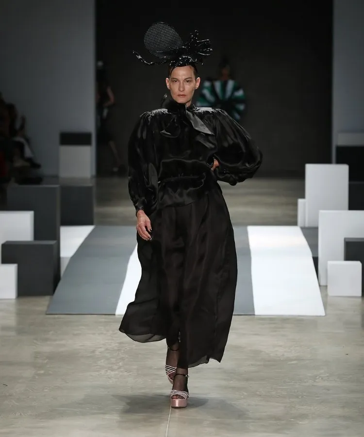 Foto de modelo na passarela usando vestido longo preto