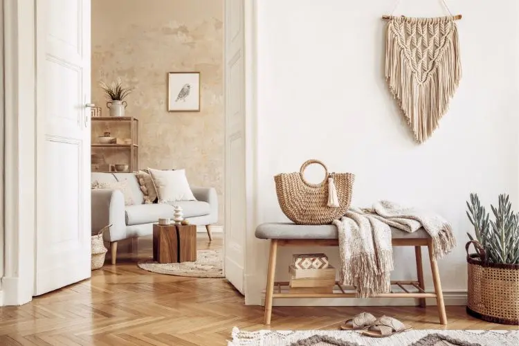 Hall e parte da sala em estilo boho, com macramê na parede, muita madeira, sofá baixo, plantas e tricô