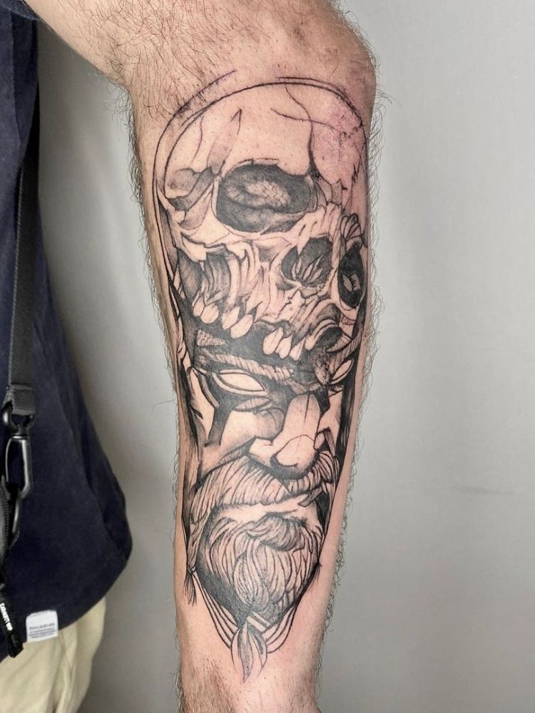foto de tatuagem de caveira e feição masculina pelo antebraço.