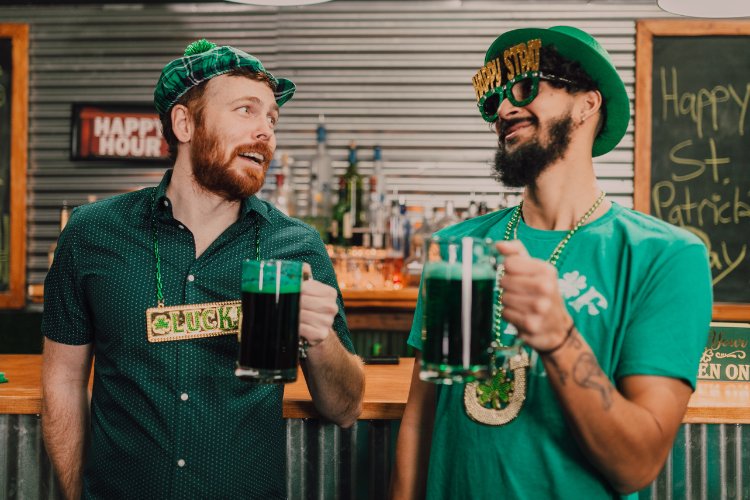 Homens de pele clara usando verde e brindando de cerveja verde