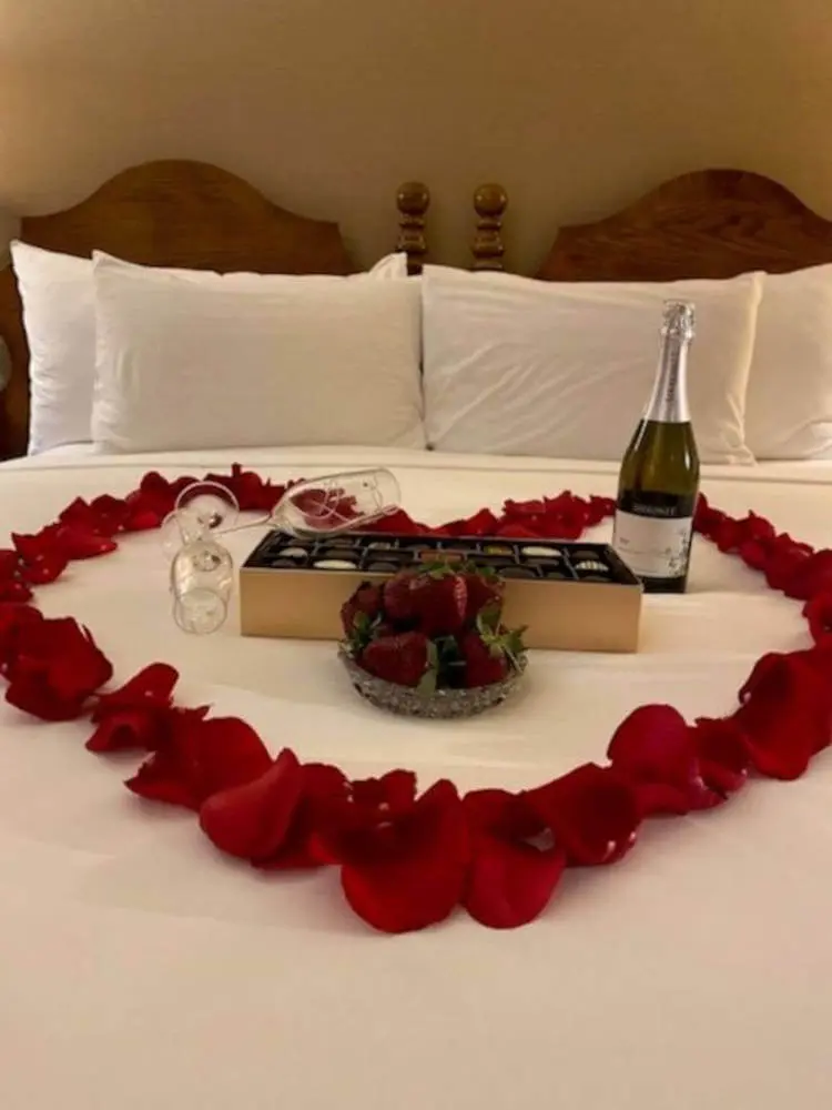 Decoração de quarto romântico com comida. Cama com caixa de bombons, morando e champagne.