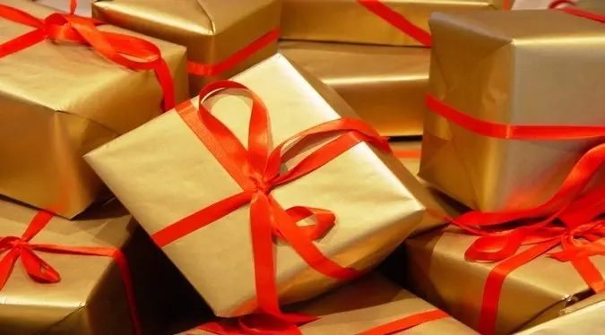 Caixas de presenta embrulhadas em dourado com fita vermelha