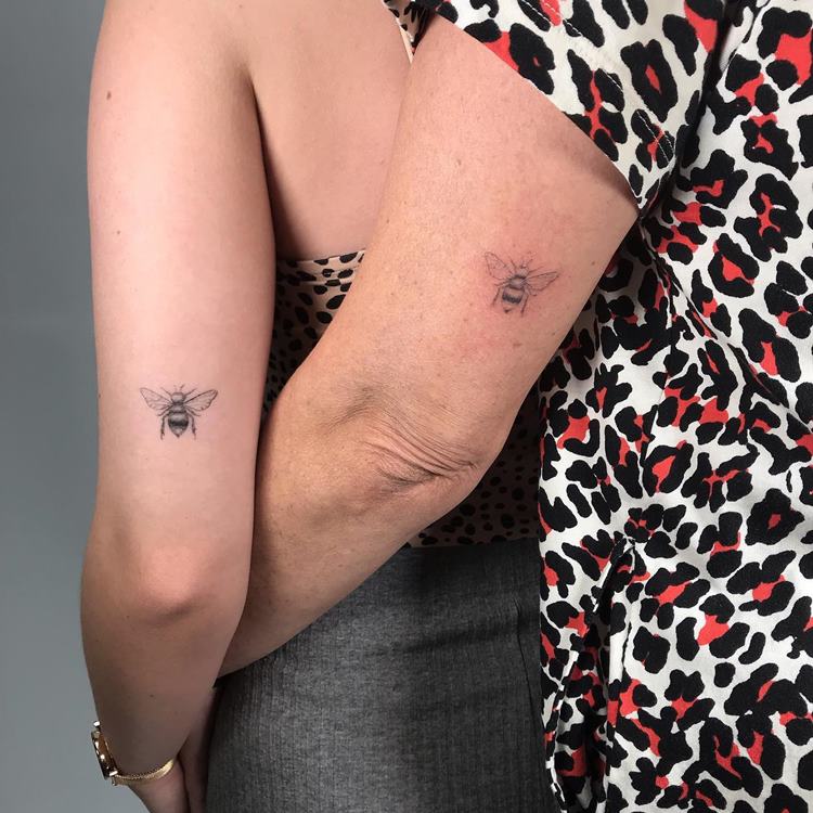 Tatuagens de abelha traço fino na aprte de trás dos braços de mãe e filhja