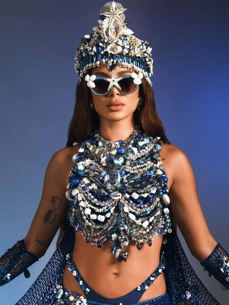 Anitta usando top, óculos e tiara com conchas, pérolas e búzios