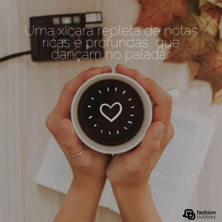Pessoa de pele clara segurando xícara de café com as duas mãos e frase 'Uma xícara repleta de notas ricas e profundas, que dançam no paladar"
