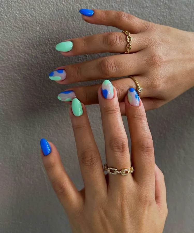 Nail art nas cores: azul, verde e branco. Desenho de: ondas.