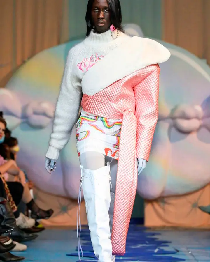 Modelo com roupa branca colorida e casaco rosa.