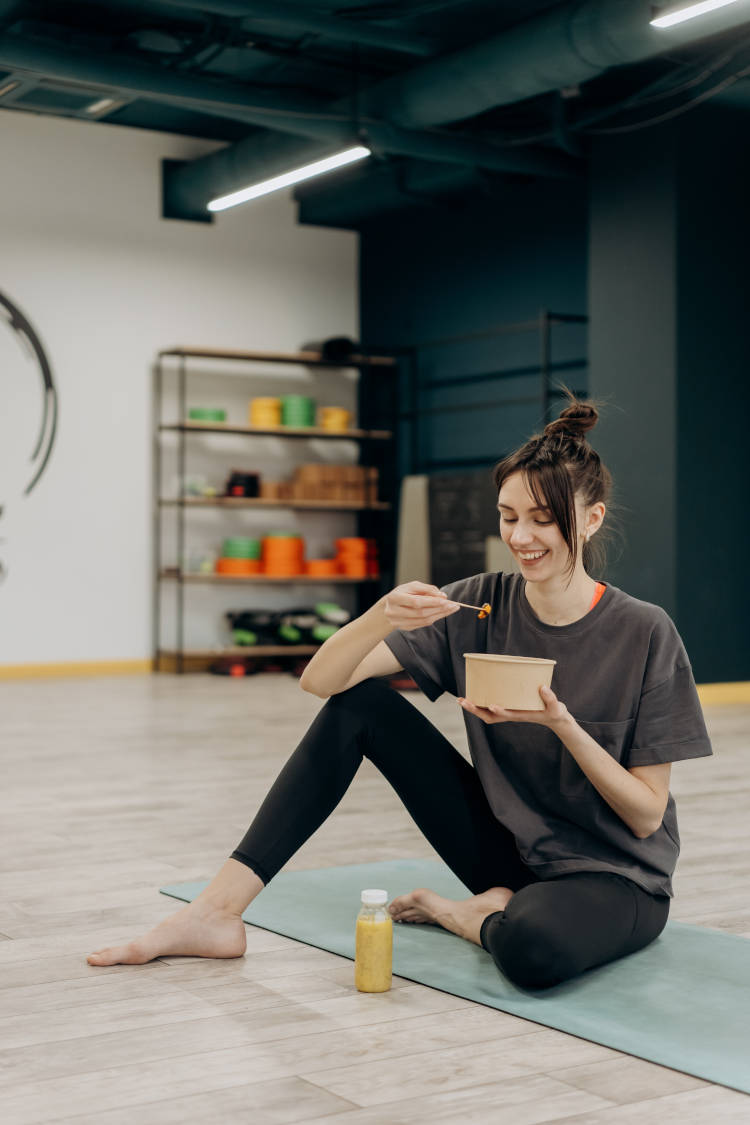 Alimentação pré-treino saudável. Mulher comendo no estúdio de yoga.