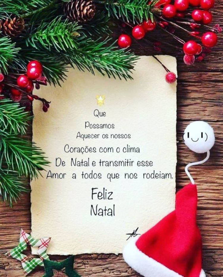 Mesa de madeira com enfeites natalinos e papel com frase: Que possamos aquecer os nossos corações com o clima de Natal e transmitir esse Amor a todos que nos rodeiam. Feliz Natal! 