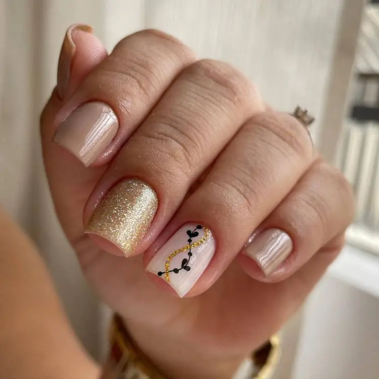 unhas cutas quadradas em bege, dourado e desenho de corações pretos