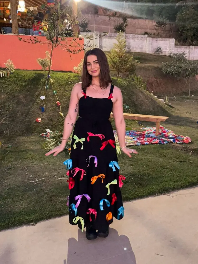 Mulher de pele clara em festa junina usando vestido preto com laços coloridos 