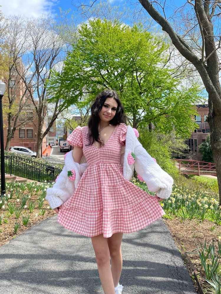 Mulher de pele clara com vestido vichy vermelho  curto com babados e cardigan branco 