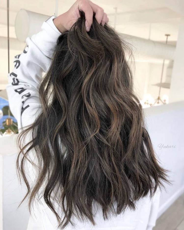 Mulher de pele clara segurando cabelo castanho