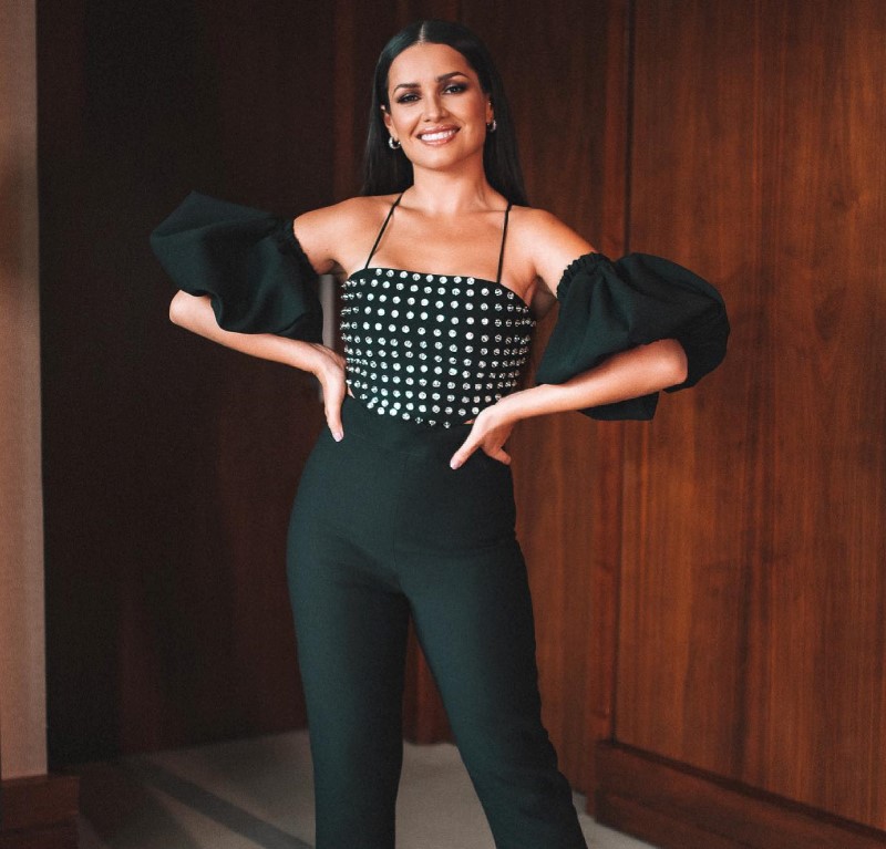 Juliette posando com um modelo preto decotado com tachas e mangas bufantes.