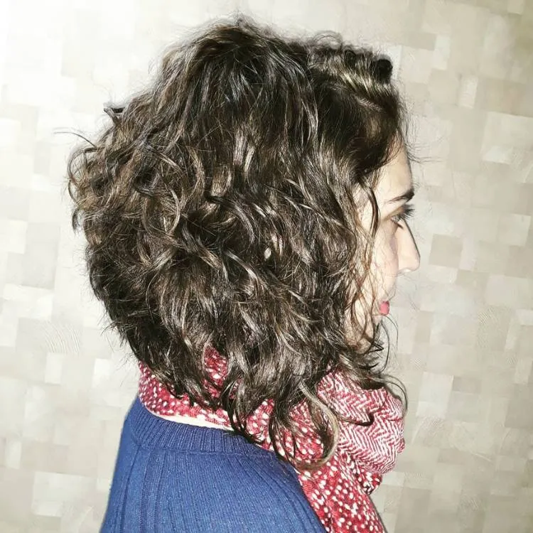 Mulher de pele clara de lado usando chanel de bico no cabelo cacheado