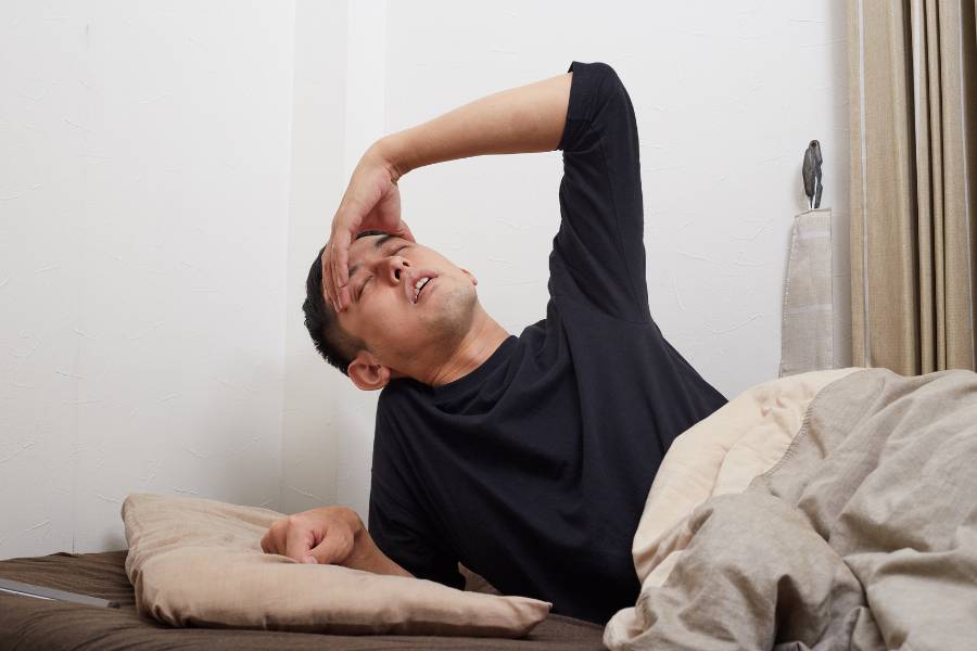 Homem deitado na cama com ressaca.