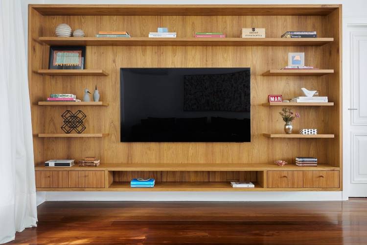Estante em madeira, com televisão, livros, quadro e outros itens decorativos. 