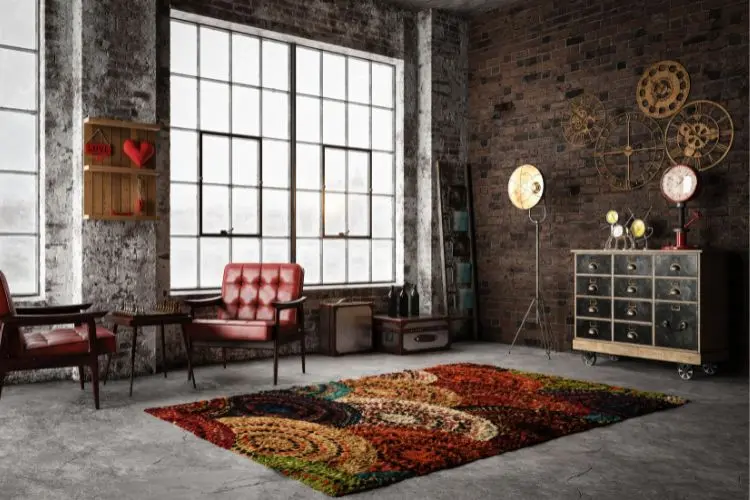 Sala estilo industrial, com grandes janelas, tijolo à vista, decoração industrial, tapete colorido e poltronas vermelhas