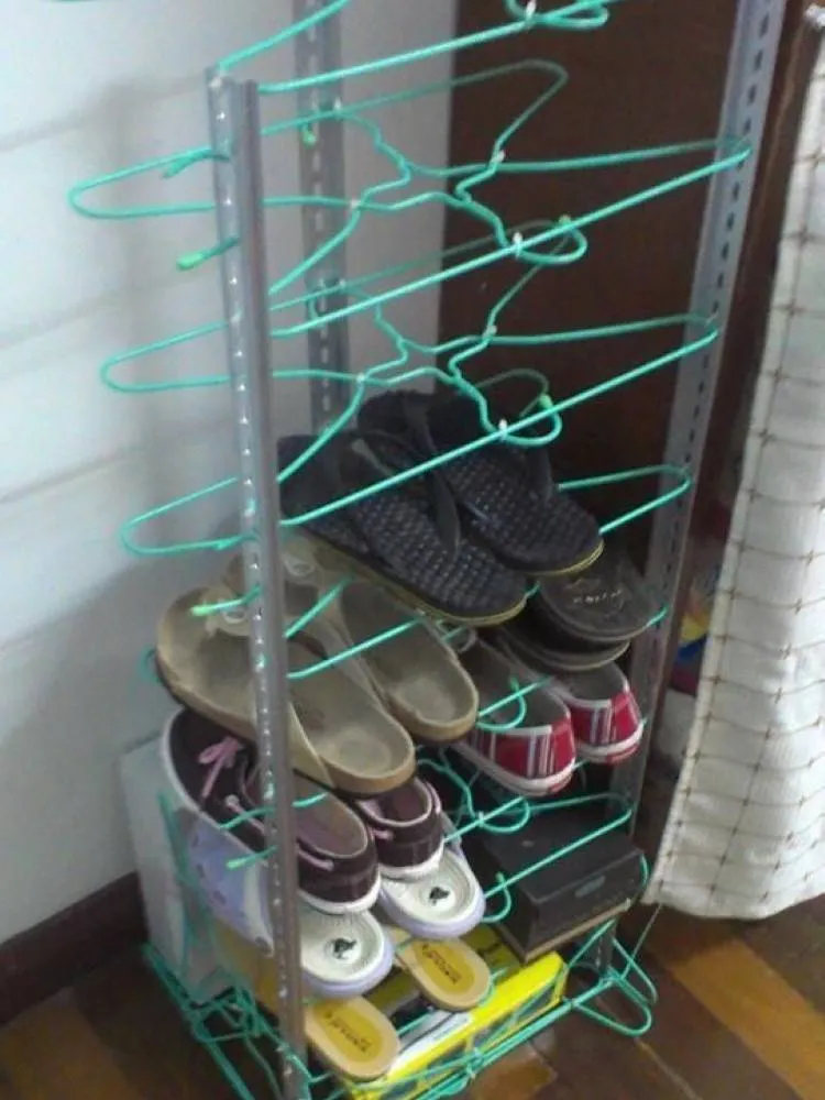 Sapateira de estrutura de metal com as prateleiras sendo dois cabides verdes. Nelas, estão armazenados alguns sapatos. 