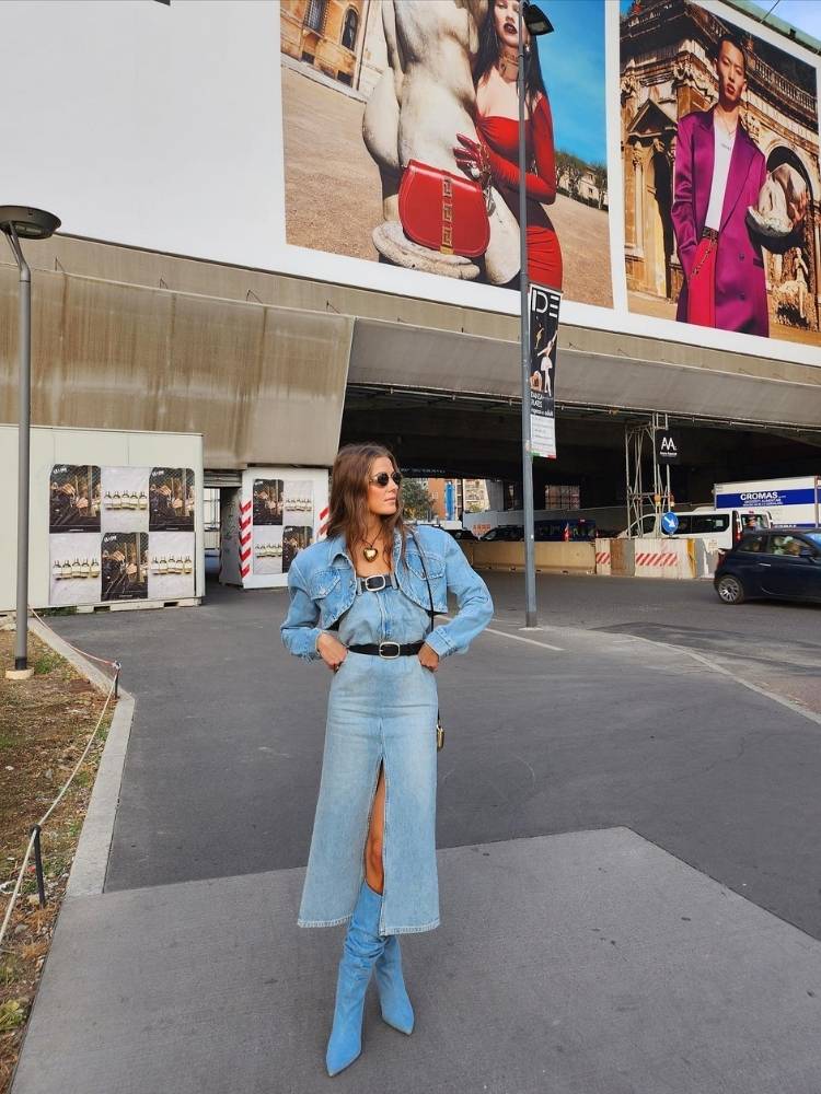 Mulher de pele clara usando look all jeans: vestido, jaqueta e bota