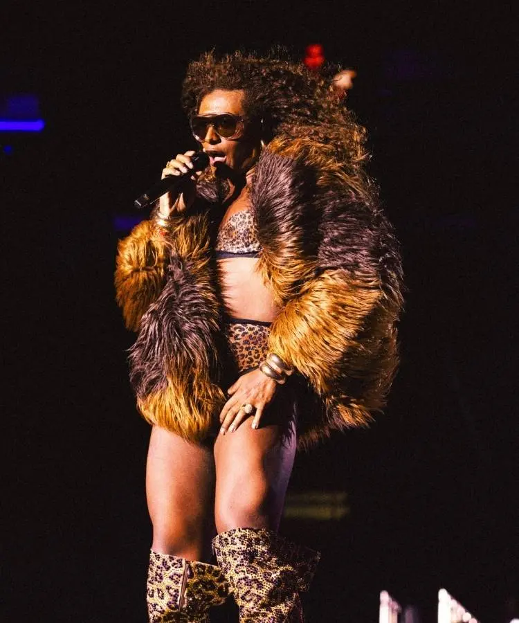 Liniker usando top e hot pants de onça com casaco de pelos na turnê BYE BYE CAJU