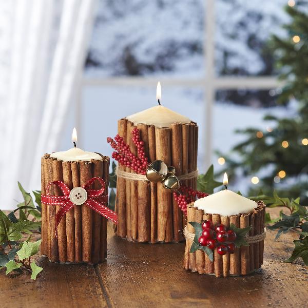 Foto de mesa com velas envoltas de canela em pau com enfeites