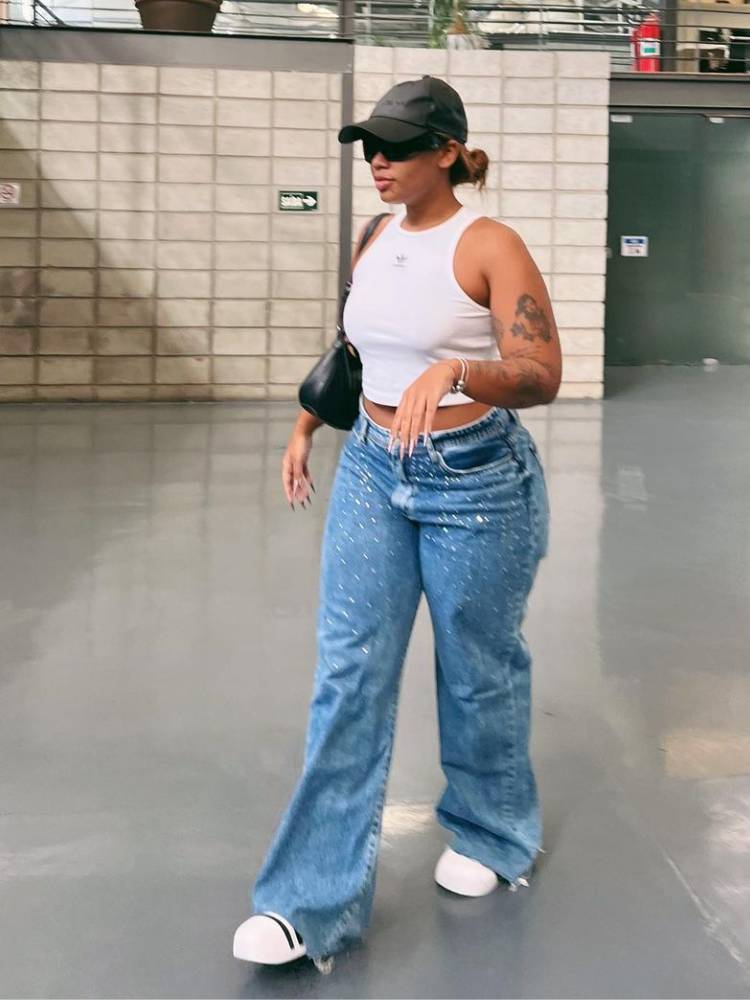 mulher usando regata cropped branca Adidas com calça jeans e tênis