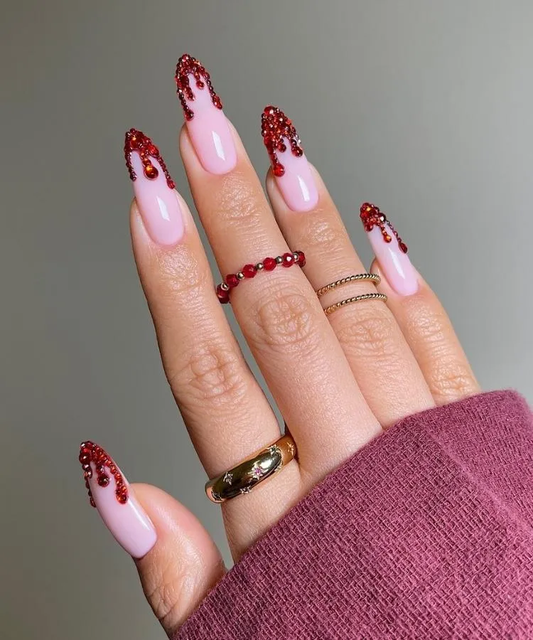 Mão com unhas longas decoradas com imitação de sangue e strass