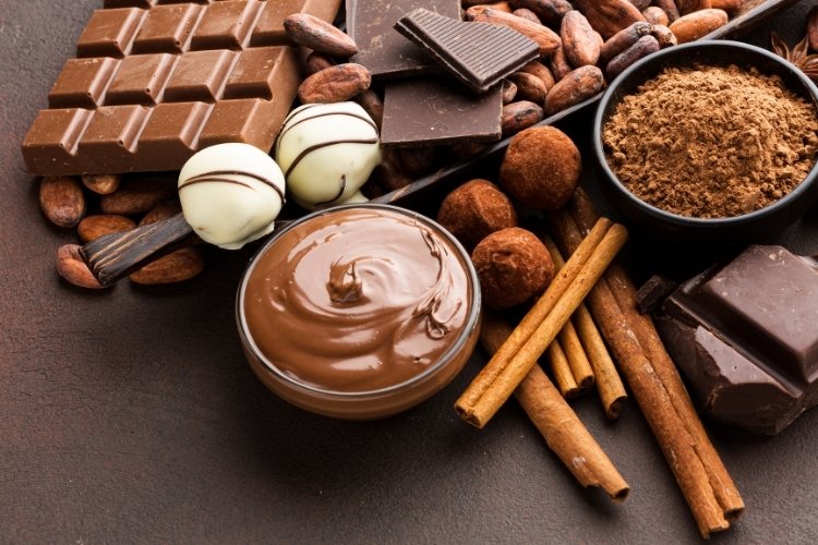 Mesa marrom com chocolates em trufas, derretido em pote e me barra